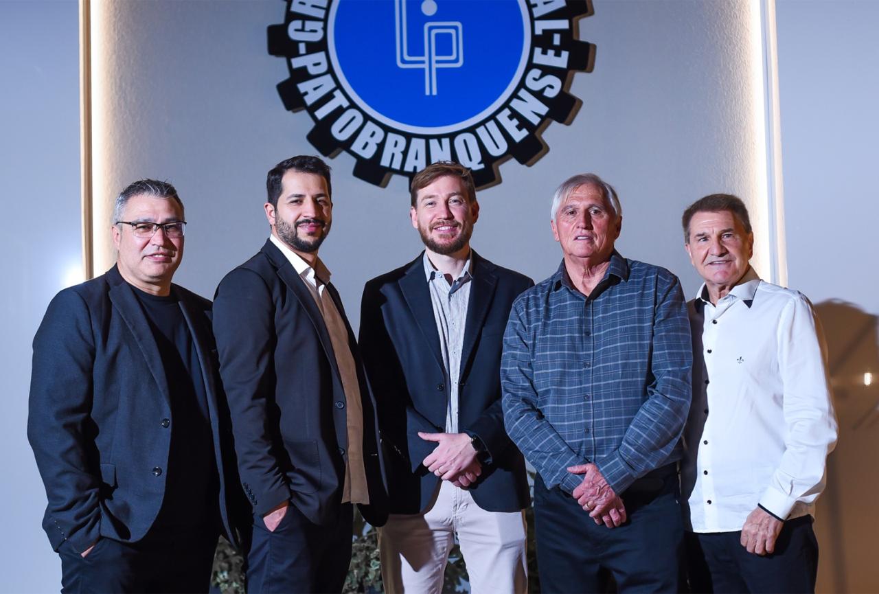 Diretoria do Grêmio Industrial Patobranquense reunida diante do brasão do clube