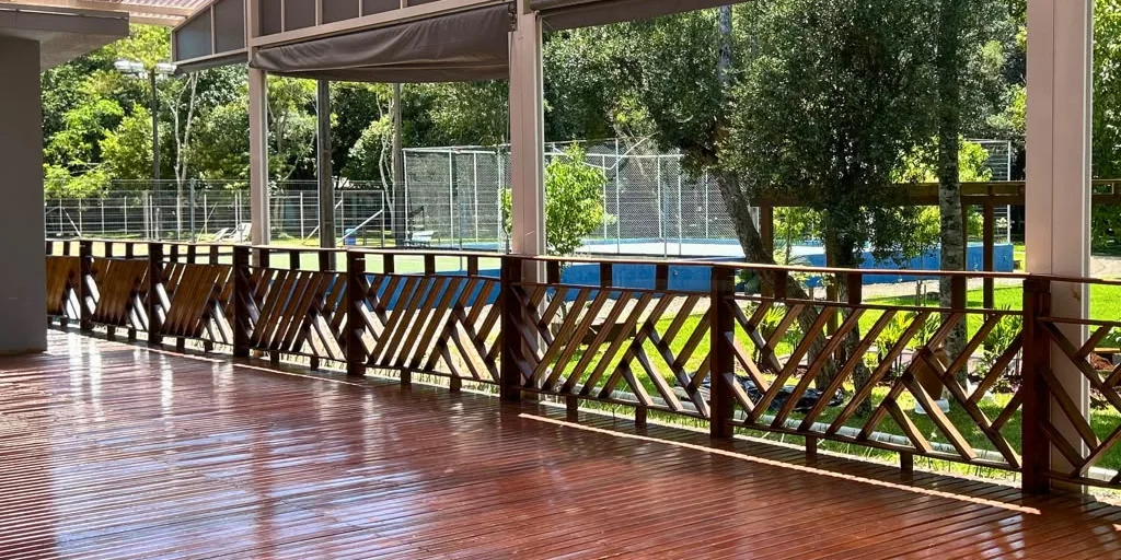 Espaço coberto do clube, com deck de madeira e vista para o verde