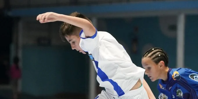 Disputa de bola em partida de futsal na quadra do clube